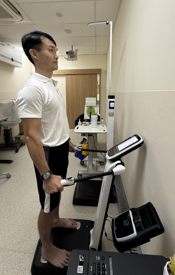 Coach Chin Hock standing on a body composition scanner during the measurement
